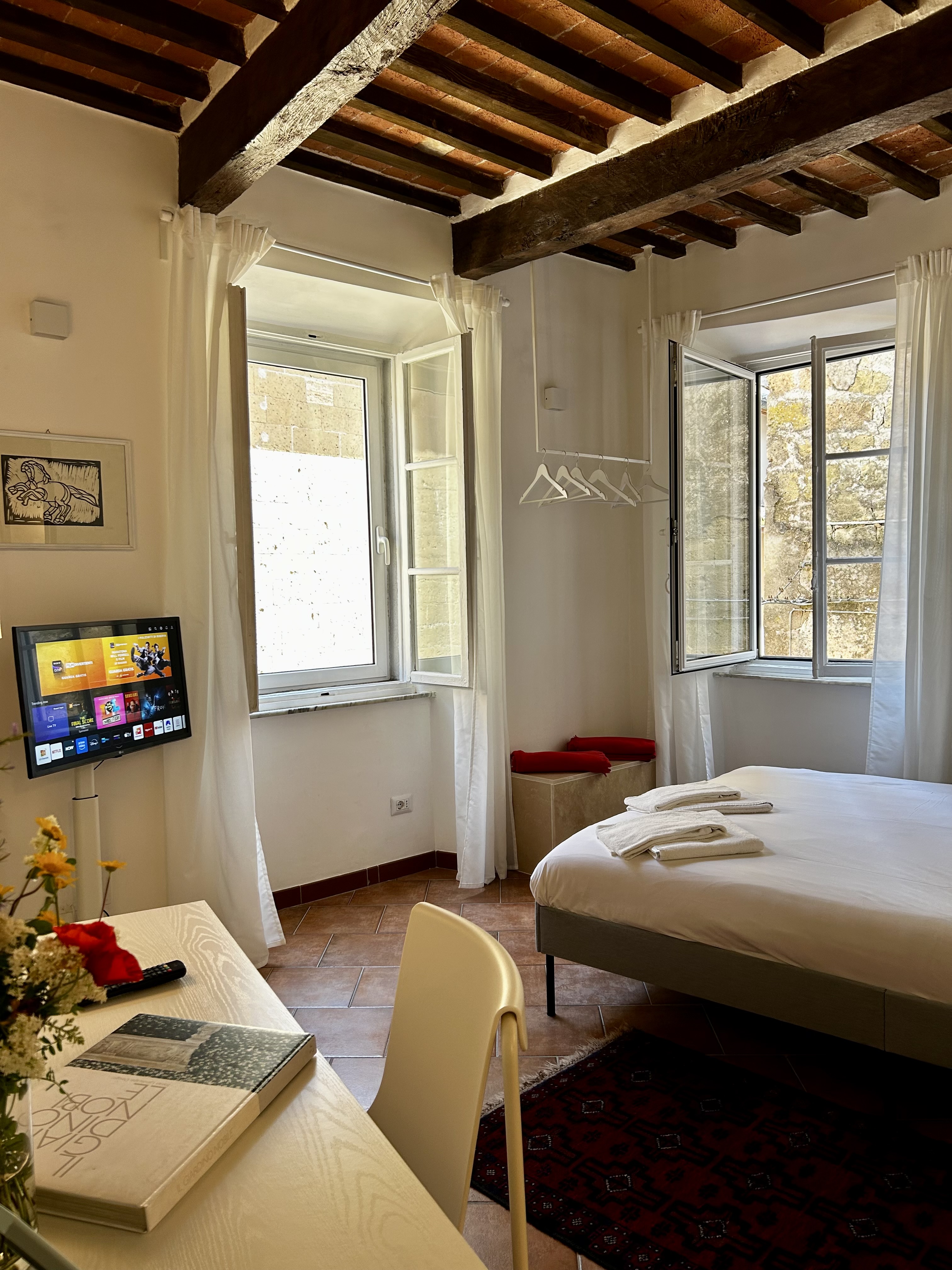 Bedroom corner with timber ceiling and open windows.