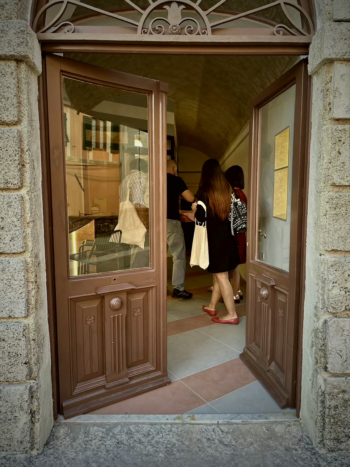 Guests arriving through the open piazza door of the Locale della antica farmacia.