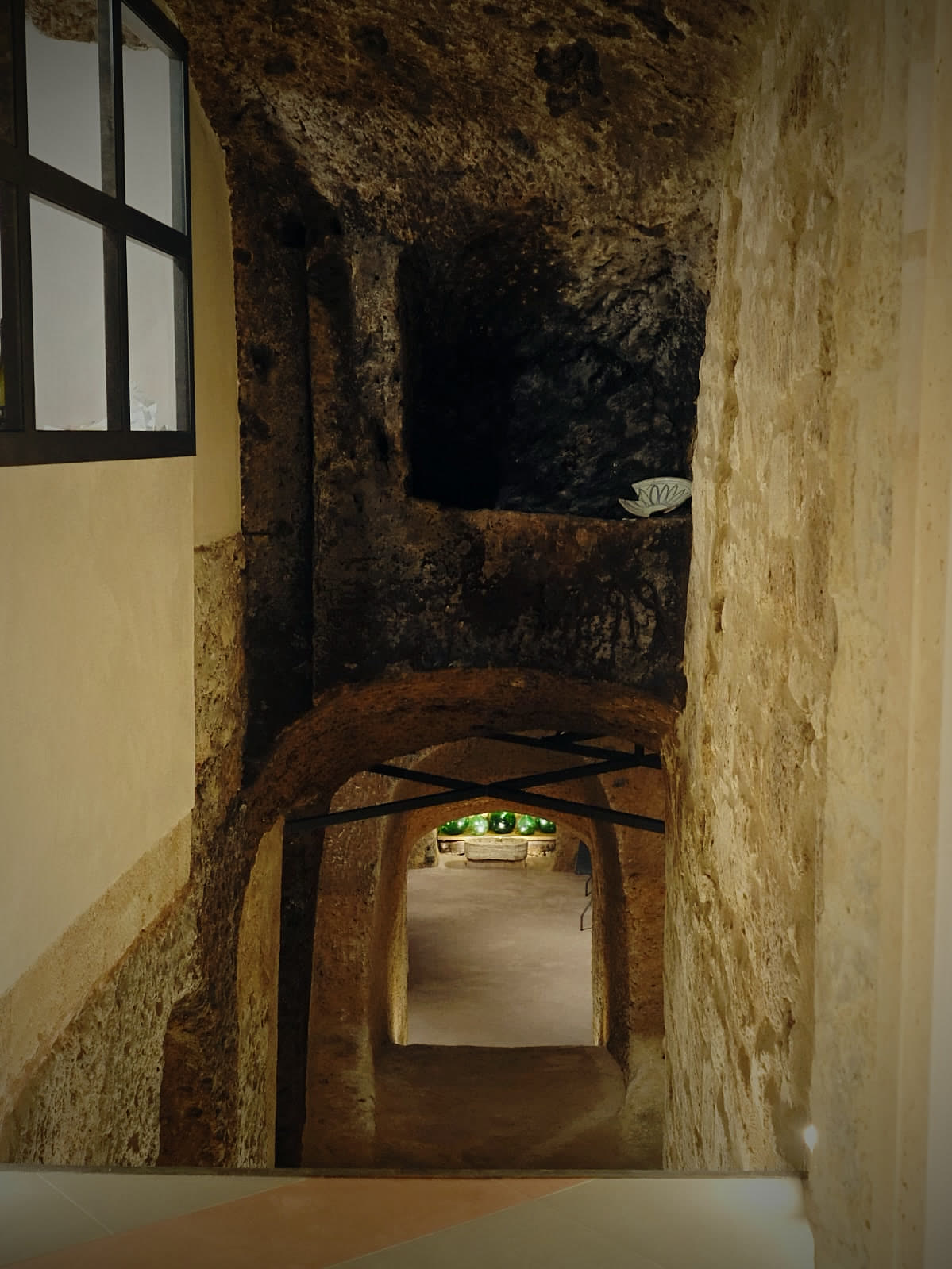 The tuff cellar's carved arches, lit from within.