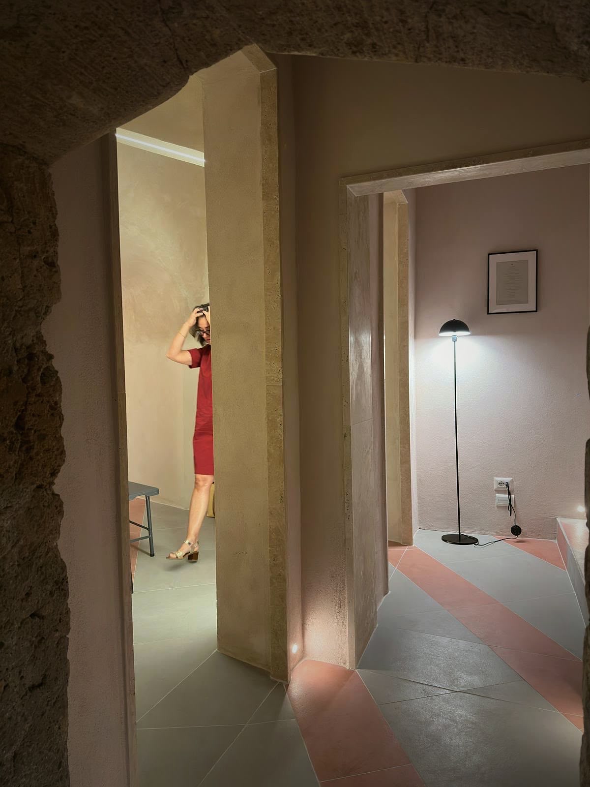 Inside the Locale — warm plaster rooms and a striped travertine floor, framed by the raw tuff.