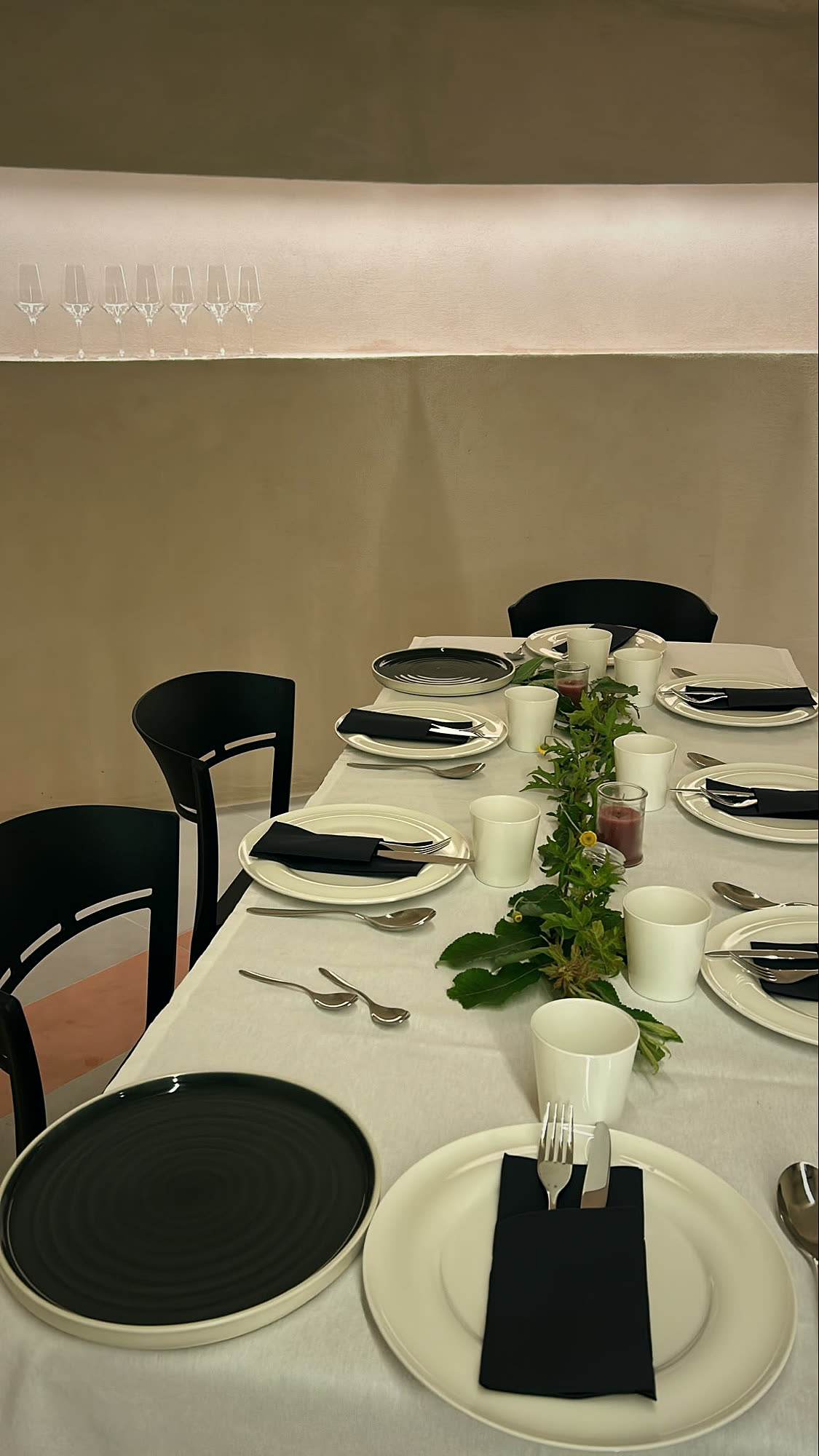 The sala, set for a seated dinner beneath a niche of glasses.
