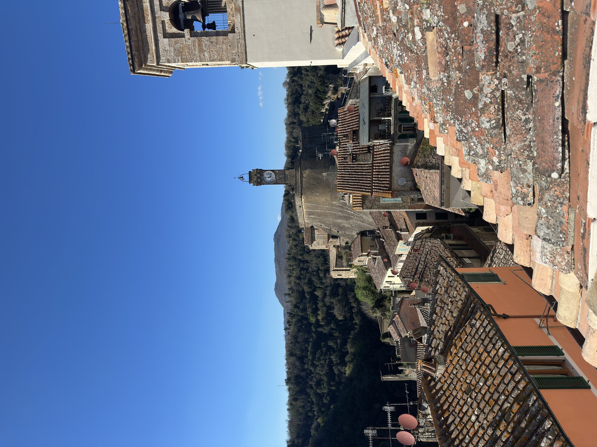 Sorano rooftops at dusk — terracotta tiles, cliff drop, distant valleys.